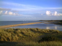 Flooded beach at Shell Bay, on Studland, Dorset, UK, with Marram grass beds in foreground