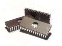 Microchips with a transparent window, showing the integrated circuit inside. Note the fine silver-colored wires that connect the integrated circuit to the pins of the package.