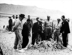 Oppenheimer, Groves, and others at the site of the Trinity test shortly after the bombings of Hiroshima and Nagasaki.