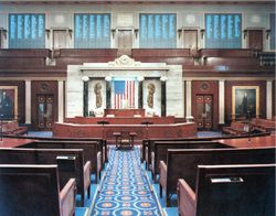 The chamber of the United States House of Representatives is located in the south wing of the Capitol building, in Washington, D.C. This photograph shows a rare glimpse of the four vote tallying boards (the blackish squares across the top), which display each member's name and vote as votes are in progress. The screens are famously used by Congressional leaders to identify which members are voting against party lines.