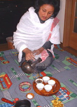 Woman coffee farmer filling cups with coffee in Ethiopia.