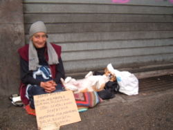 A homeless woman with her dog in a street of Rome